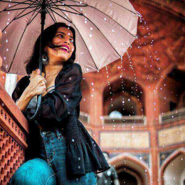 Girl wearing an apt outfit for rainy day. Holding an umbrella and smiling.