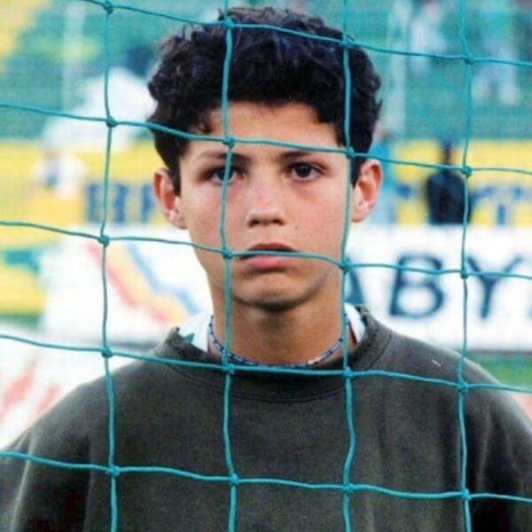 Young Cristiano Ronaldo stand behind the net of the football goal post
