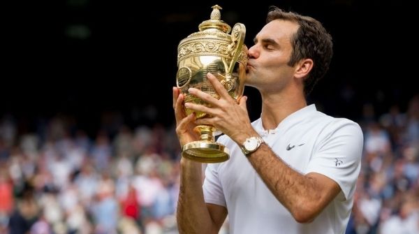 Roger Federer holding his Wimbledon Grand Slam Cup and kissing it